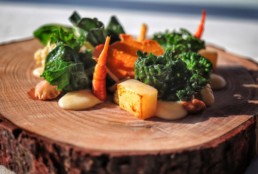 Su un piatto che ricorda la sezione di un tronco, carote, patate e diverse verdure dell'orto del ristorante